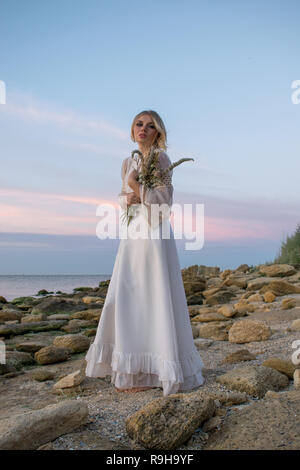 Jeune femme élégante en robe blanche sur fond de mer Banque D'Images