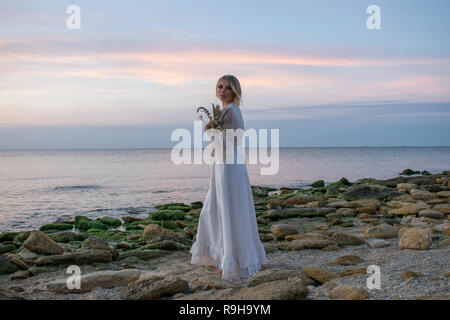 Jeune femme élégante en robe blanche sur fond de mer Banque D'Images