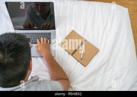 Vue arrière du Young Asian man working on bed Banque D'Images