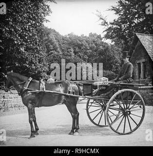 Un style victorien anglais noir et blanc photographie montrant un petit cheval et chariot avec un cavalier ou chariot conducteur assis dans le chariot. Le conducteur du chariot est vêtue de vêtements très fin, un bon exemple de la mode de l'époque. Banque D'Images