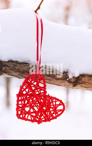 Vintage romantique coeur est suspendu par une bande rouge sur un fond blanc de la neige. L'amour et du concept de Jour de Valentines Banque D'Images