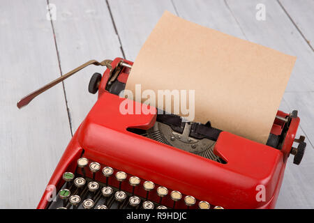 Machine à écrire vintage rouge avec feuille de papier blanc sur la table en bois blanc Banque D'Images