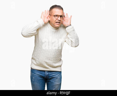 L'âge moyen de l'homme arabes portant des lunettes au fond isolé essaie d'écouter les deux mains sur le geste de l'oreille, curieux de ragots. Problème d'audition, sourds Banque D'Images