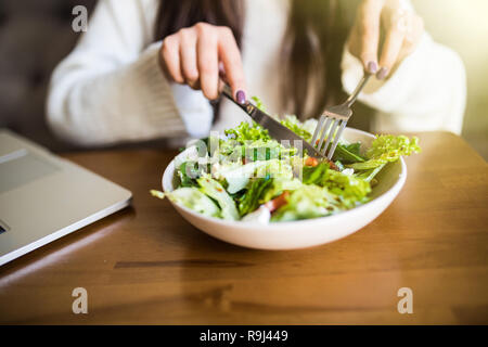 Close up attractive woman hand holding fourchette et cuillère pour manger une salade de légumes au déjeuner dans le café. Banque D'Images