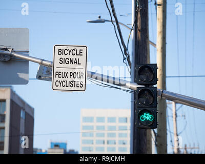 Location de feu vert et d'Amérique du Nord roadsign en anglais et en français indiquant le signal est seulement pour les vélos, sur une piste cyclable au centre-ville o Banque D'Images