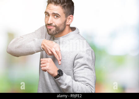 Beau jeune homme portant un sweat-shirt sur fond isolé en hâte, se dirigeant à l'heure, l'impatience, en colère et pour délai retard Banque D'Images