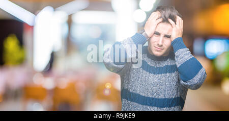 Jeune homme séduisant sur fond isolés souffrant de maux désespérés et souligné parce que la douleur et la migraine. Les mains sur la tête. Banque D'Images