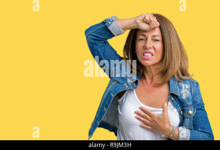 Belle femme d'âge moyen portant veste en jean décontracté sur fond isolé Touching forehead pour maladie et la fièvre, la grippe et le froid, malade du virus Banque D'Images