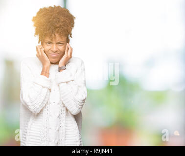 Beau young african american woman wearing winter sweater sur fond isolé couvrant les oreilles avec les doigts avec de l'expression ennuyé nois Banque D'Images