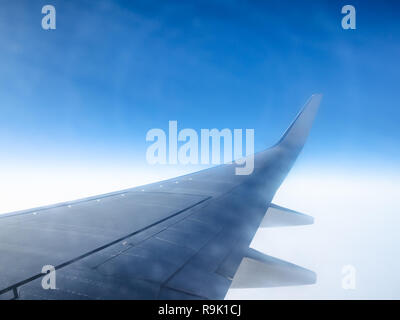 Vue de l'aile et phénomènes de halo dans le ciel bleu pendant le vol à travers un hublot Banque D'Images