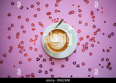 Un délicieux cappuccino parfumé sur fond de fête avec beaucoup de cœurs. Concept pour la Saint Valentin ou la Journée de la femme. Banque D'Images