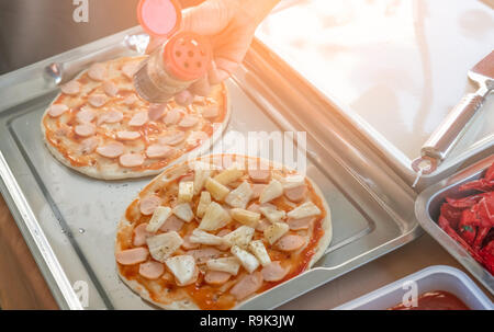 Femme faire la pizza pour faire un don à l'événement de bienfaisance avec croûte à pizza et l'ananas. Femme chef preparing pizza avec des mains mettre les ingrédients de la pi Banque D'Images