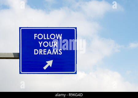 Blue road sign afficher Suivez vos rêves mots sur ciel bleu et des nuages blancs de fond Banque D'Images