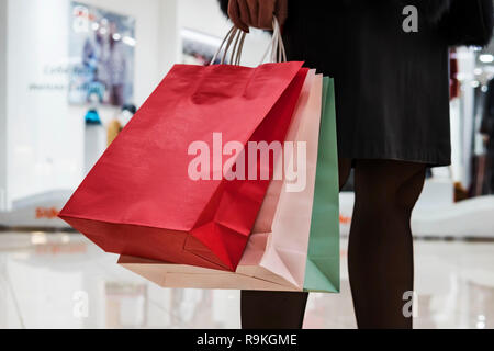 Close up de sacs en papier coloré dans le centre commercial sur l'arrière-plan. Femme en jupe et collants noirs debout dans mall passant et la maintenir Banque D'Images