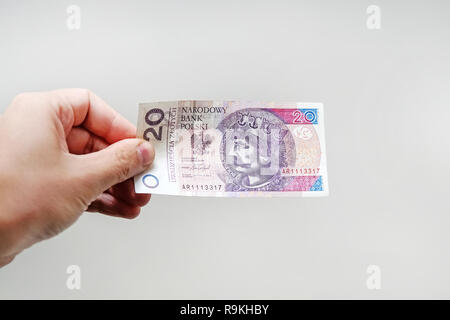 Close up sur un billet de 20 zloty dans une main d'homme. objet sur fond blanc. Banque D'Images