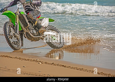 Motocycliste dans un vêtement de protection conduit une motocyclette sur la mer, les éclaboussures de voler sous les roues. Banque D'Images