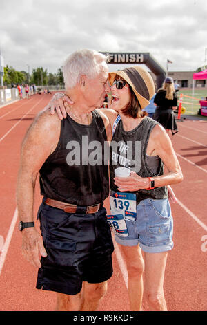 A 78 ans, homme obtient une accolade de son épouse après avoir fini à la fois une communauté course à pied dans un Costa Mesa, CA, high school stadium. Banque D'Images