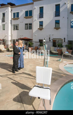 Deux résidents éventuels sur une Laguna Niguel, CA, communauté de retraite plaza inspecter un palan président de la piscine pour accueillir les nageurs handicapés. Banque D'Images