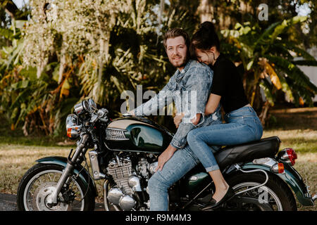 Portrait de belle à la jeune fille à la mode moderne, tendance Guy Couple Riding sur moto verte Cruiser vélo classique dans l'amour Banque D'Images