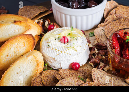 Boulangerie traditionnelle française camembert au thym et pain grillé, noix, olives, tomates séchées et copeaux de lin. Banque D'Images