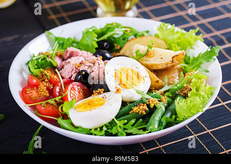 Un copieux petit-déjeuner sain salade de thon, haricots verts, tomates, oeufs, pommes de terre, olives noires close-up dans un bol sur la table. Salade niçoise. La cuisine française. Banque D'Images