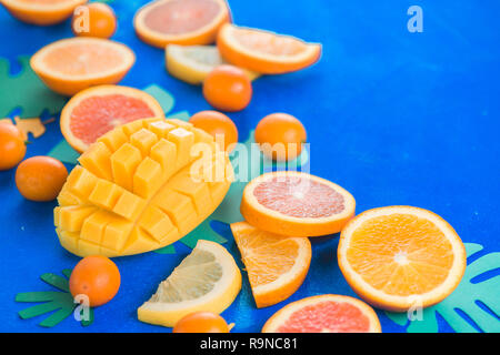 Fruits exotiques close-up. Mangues, oranges, kumquats et autres fruits tropicaux bleu fond avec copie espace. Banque D'Images