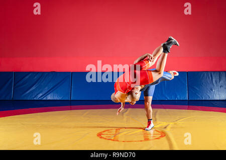 Le concept de la juste lutte. Deux lutteurs gréco-romain en uniforme rouge et bleu sur fond de lutte sur un tapis de lutte jaune dans la salle de sport Banque D'Images