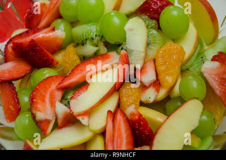 Une vue rapprochée de la salade de fruits faite de tranches de pommes, fraises, kiwim mandarin orange et raisins. Banque D'Images