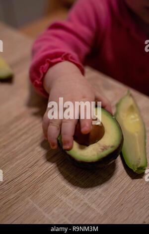 La main de l'enfant atteint de l'avocat. Une alimentation saine pour les enfants Banque D'Images