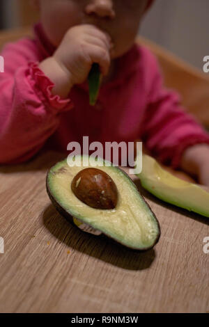 La main de l'enfant atteint de l'avocat. Une alimentation saine pour les enfants Banque D'Images