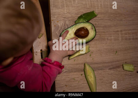 La main de l'enfant atteint de l'avocat. Une alimentation saine pour les enfants Banque D'Images