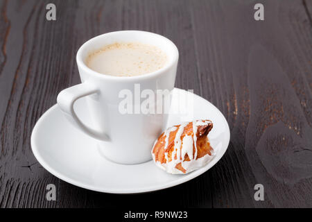 Bonbons savoureux et tasse de café sur fond de bois Banque D'Images