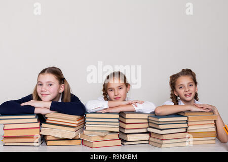 Trois filles ecolières à un bureau avec des livres sur la leçon à l'école Banque D'Images