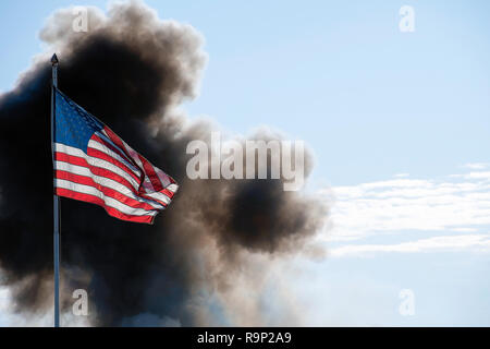 Drapeau américain illuminé par la lumière du soleil avec nuage de fumée noire Banque D'Images