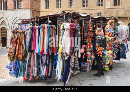 Sienne, Italie - 02 octobre 2018 : Souvenir stall avec châles en soie et les touristes la marche sur la place Piazza del Campo et le centre historique de Sienne Banque D'Images