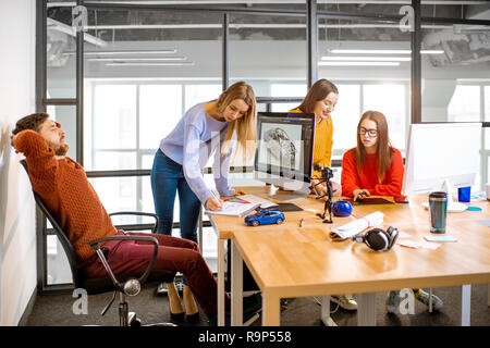 Groupe de jeunes collaborateurs créatifs de la conception d'un modèle de voiture sur le lieu de travail avec des ordinateurs dans l'intérieur de bureau moderne Banque D'Images