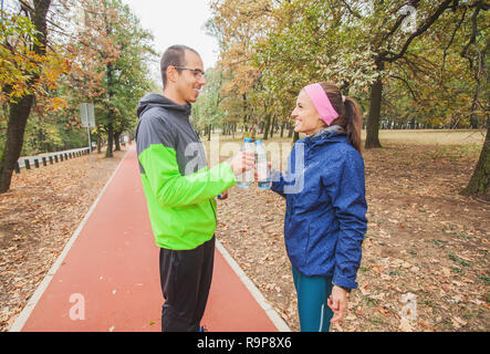 Happy young couple relaxing on parcours santé et rafraîchissant avec de l'eau suite à l'utilisation. Banque D'Images