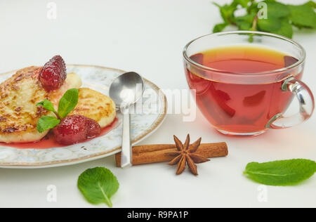 Crème glacée sur une soucoupe avec de la confiture et du thé. fromage cottage ou crêpes crêpes avec de la confiture de fraise et d'une tasse de thé sur un tableau blanc traditionnel Russi. Banque D'Images