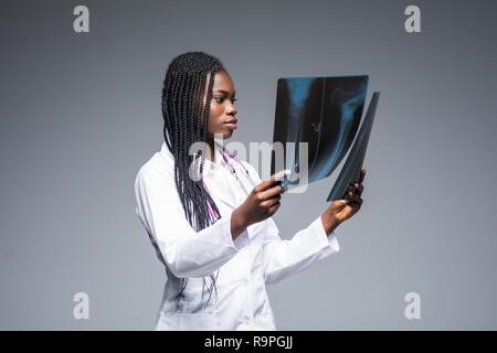 Jeune femme africaine à la recherche d'un médecin à x-ray sur fond gris Banque D'Images