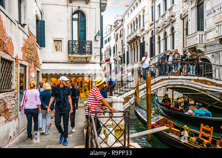 Un canal occupé à la calle de la Canonica en touristes traverser le pont avec les gondoles et les touristes un gondolier attend les clients à Venise Italie Banque D'Images