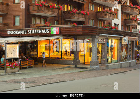 Zermatt, Suisse - 15 septembre 2018 : les bâtiments de la ville de Zermatt le long de la Bahnhofstrasse street dans la soirée, les gens à la tables o Banque D'Images