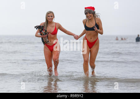 Sur la photo : Deux jeunes femmes en bikini et Santa hats run dans la mer. Le mardi 25 décembre 2018 Re : des centaines de personnes prennent part à cette année, l'Porthcaw Banque D'Images