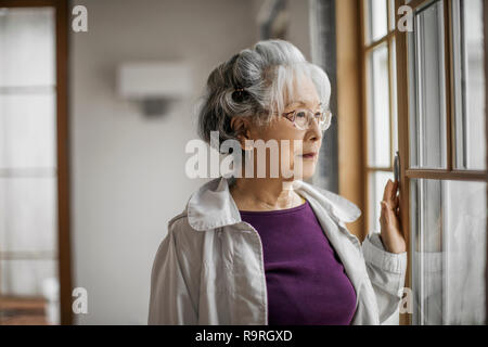 Portrait of a smiling woman regarder par la fenêtre. Banque D'Images