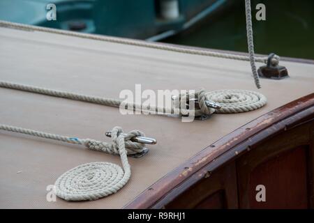 Détail de l'endroit parfait, soigné des cordes enroulées à côté d'un taquet sur le pont d'un bateau en bois Banque D'Images