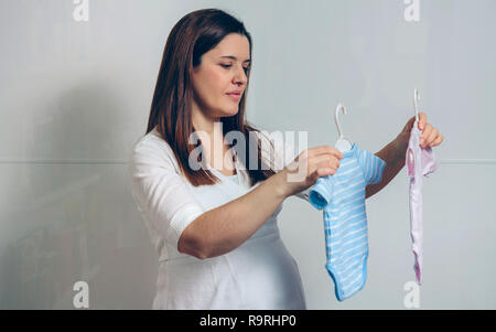 Femme enceinte choisir rose ou bleu baby bodysuits piscine Banque D'Images