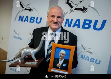 Berlin, Allemagne. 28 Dec, 2018. L'Olaf Tschimpke, Président de l'Association de la protection de la nature Nabu, montre une photo et le trophée de la RWE CHEF R. M. Schmitz après la conférence de presse d'attribuer le 'Dinosaur de l'année 2018'. La raison donnée pour le prix a été négative que Schmitz insiste tant sur l'effacement de la forêt de Hambach pour la mine de lignite à ciel ouvert, il y avait de plus de plus en plus polarisé le débat passionné sur la protection du climat. Credit : Kay Nietfeld/dpa/Alamy Live News Banque D'Images