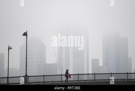 Frankfurt am Main, Allemagne. 29 Dec 2018. Un marcheur marche à travers le pont radeau à portée de vue de la banque towers enveloppé dans le brouillard. Photo : Arne Dedert/dpa dpa : Crédit photo alliance/Alamy Live News Banque D'Images