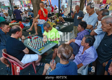 Les hommes d'origine chinoise à Kreta Ayer Square, Chinatown, Singapour, plongé dans la lecture d'une version chinoise de chess, attirant de nombreux spectateurs Banque D'Images