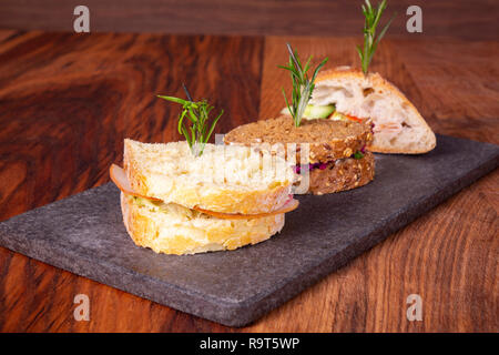 Trois des sandwichs avec de la salade, du jambon, du fromage et des tomates sur la table de marbre. Banque D'Images