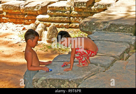 Enfants jouant avec de petites voitures près de temple, Angkor, Cambodge Banque D'Images